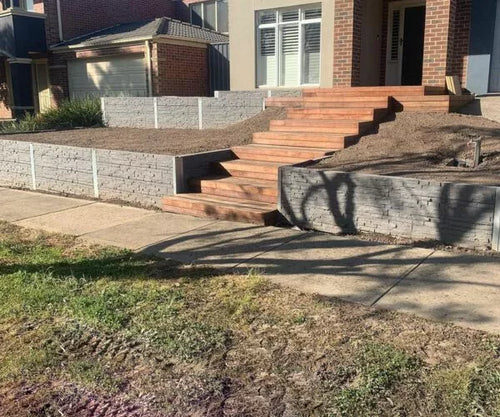 landscaping project featuring a retaining wall and a set of wooden stairs leading up to a house.